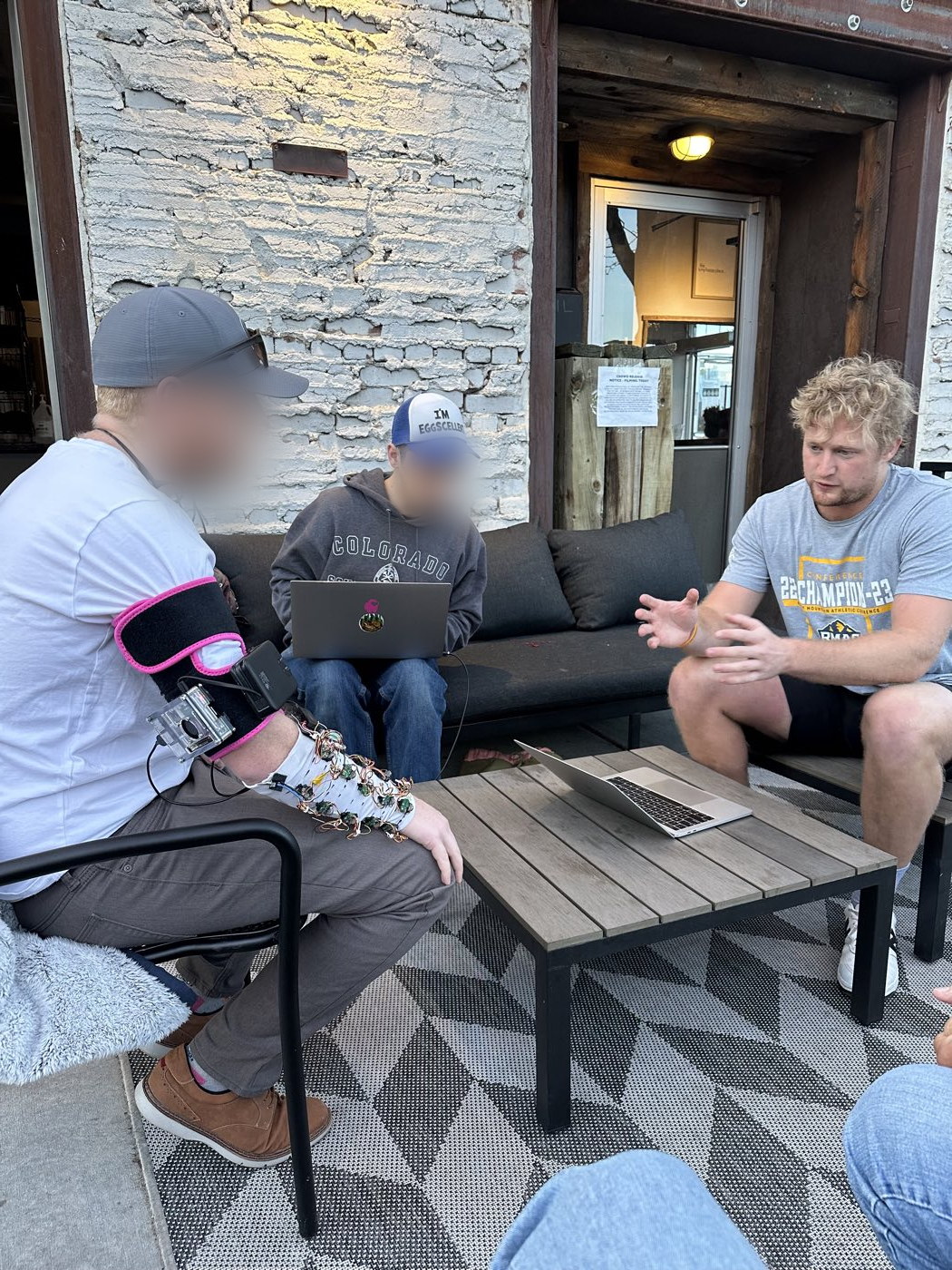 The team testing the early rig with a user, laptops open on a patio table